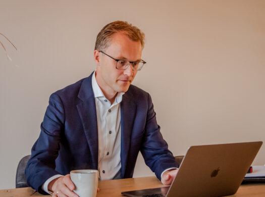 Makelaar achter laptop met koffiemok